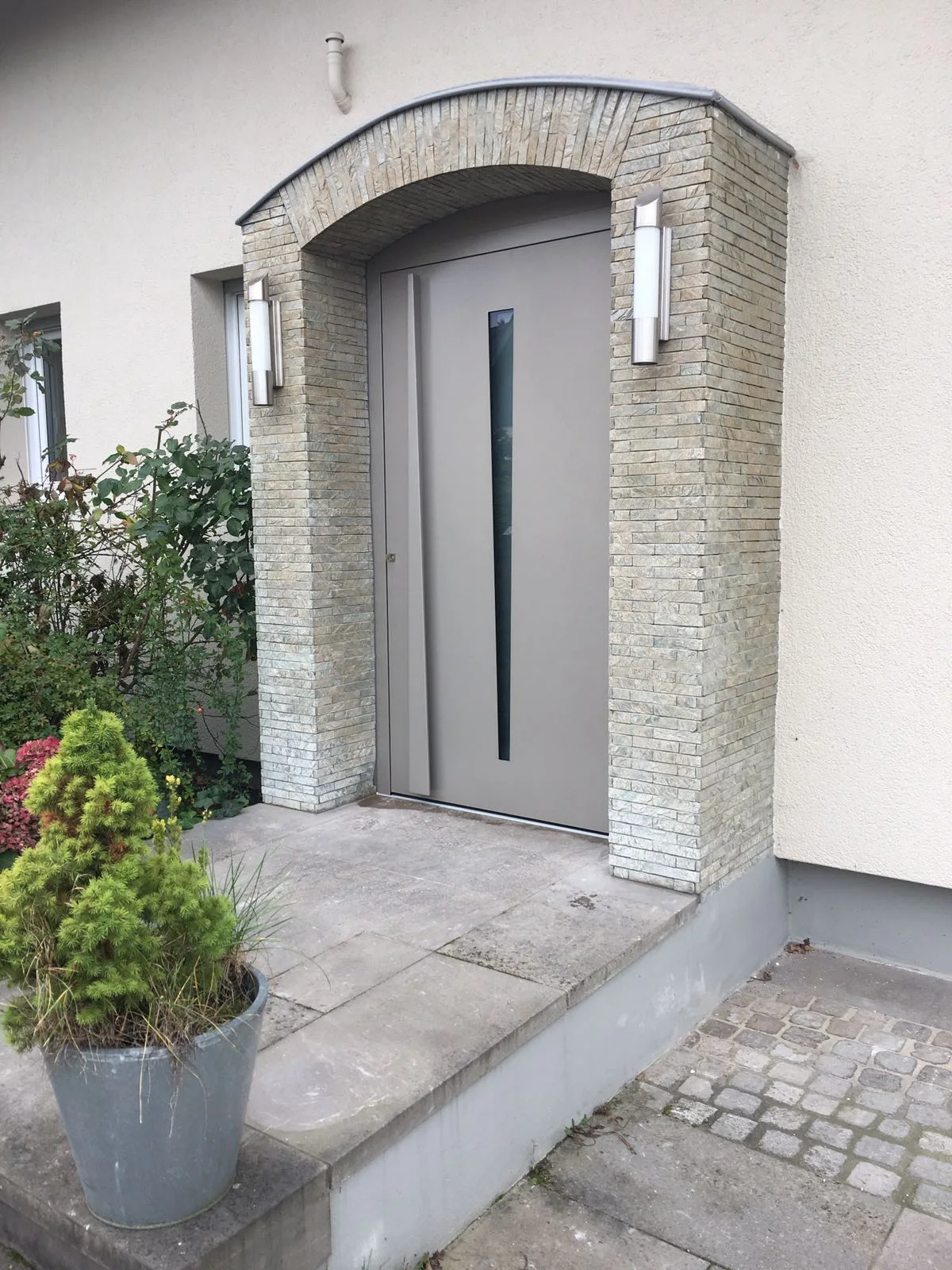 Graue Haustür unter einem Steinbogen