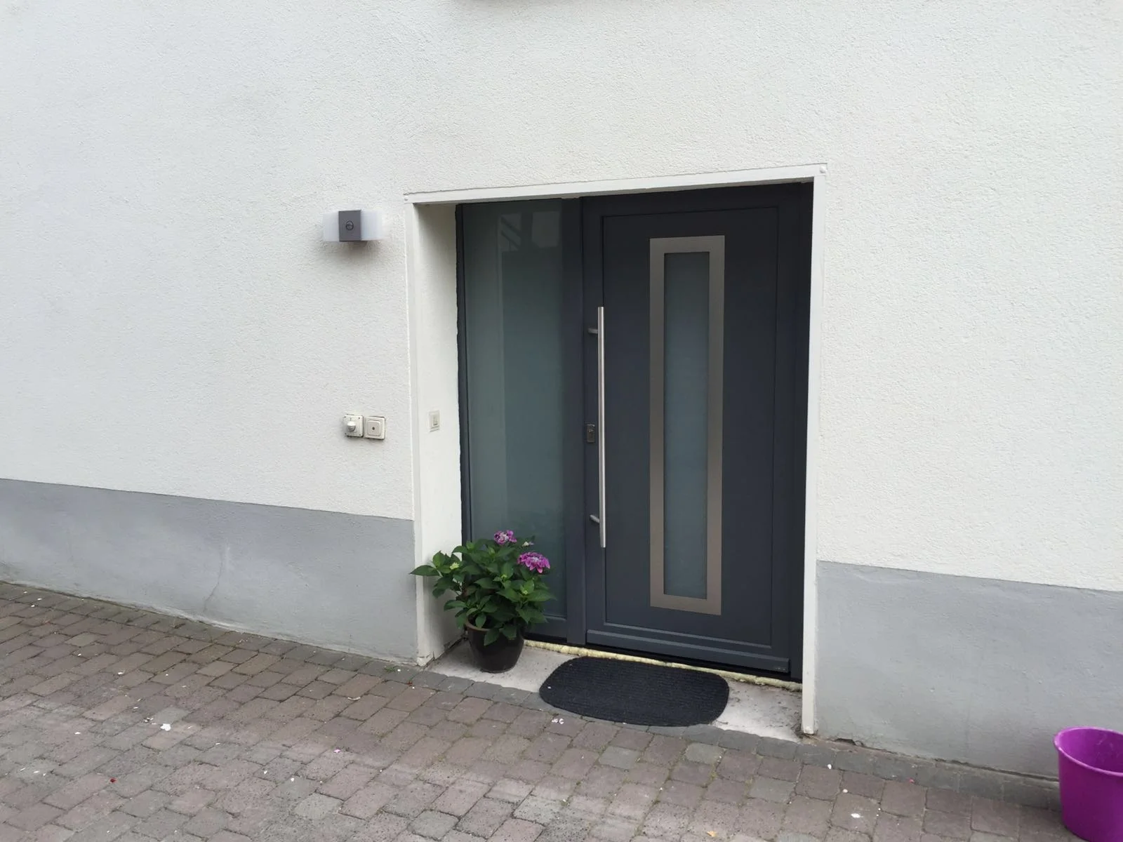 Eingebaute graue Haustür mit verglastem Seitenteil