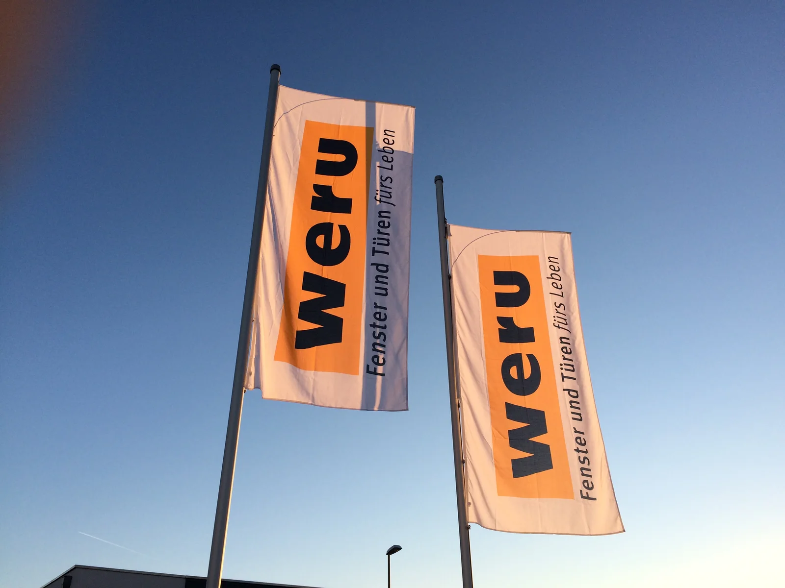 WERU-Fahnen vor blauem Himmel am Betrieb in Kelkheim-Münster